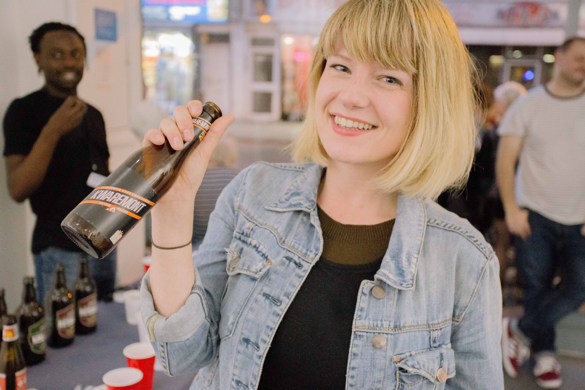 Woman holding a bottle of branded beer at an experiential and marketing event held in London produced by Barefaced Studios - design agency in the UK.